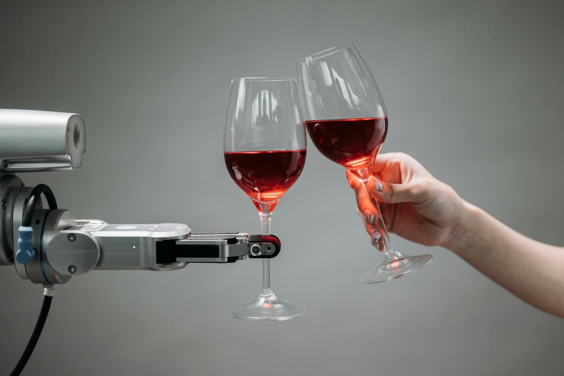 Automation Benefits - Robotic arm and human hand with wine glasses representing collaboration between automation and human creativity